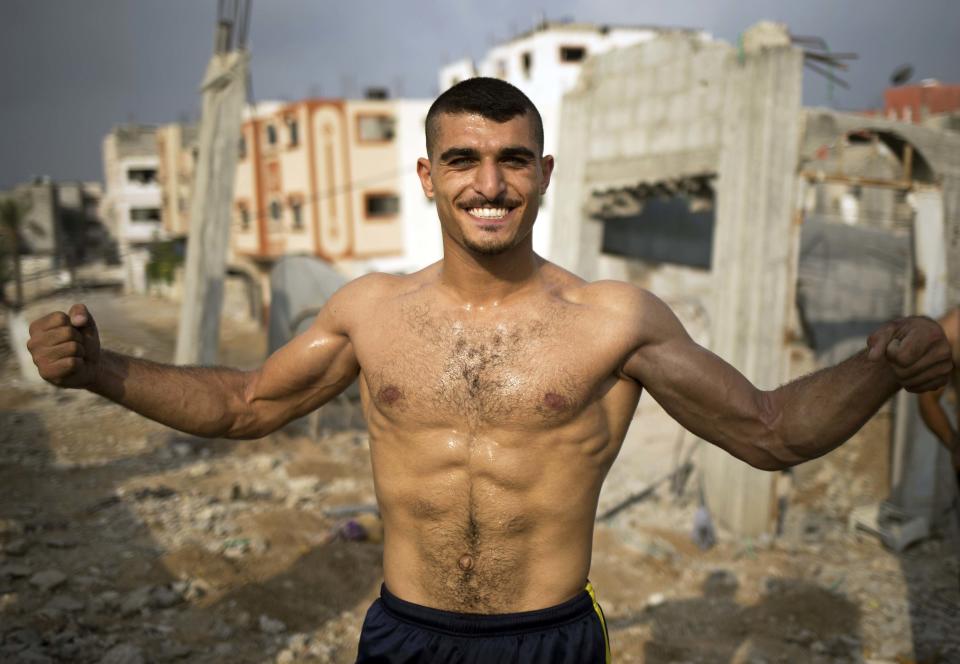 Palestinian Bakr al-Makadmeh, of Bar Palestine group, flexes his muscles during street exercises amid the destruction in Gaza City on August 3, 2015. Street workout, that is still new to Gaza, is a growing sport across the world with annual competitions and events. 