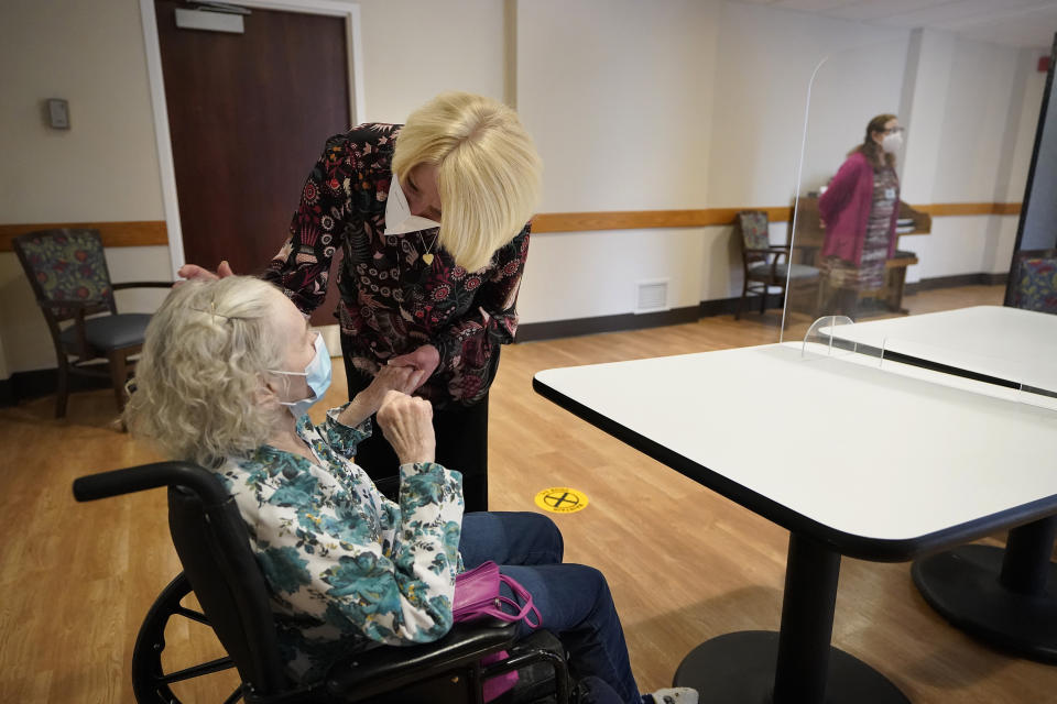 FILE - In this March 18, 2021, file photo, Mary Claire Lane, 86, left, a resident at Hellenic Nursing and Rehabilitation Center, in Canton, Mass., is greeted by her daughter Anne Darling, of Attleboro, Mass., center, during a visit, at the nursing home, in Canton. Nursing homes have to publicly disclose their vaccination rates for flu and pneumonia, but there’s no similar mandate for COVID-19 shots. (AP Photo/Steven Senne, File)