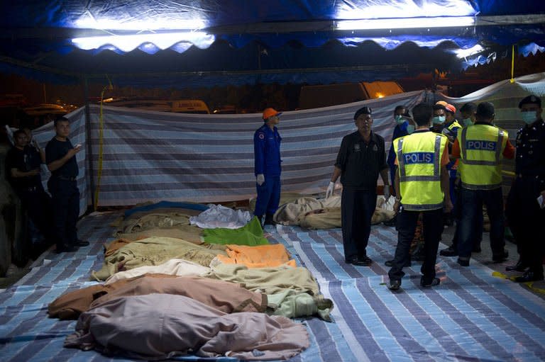 Victims lie lined up on the ground after a bus carrying tourists and local residents fell into a ravine near the Genting Highlands, about an hour's drive from Kuala Lumpur on August 21, 2013. At least 20 people are confirmed dead and the toll was expected to climb after a bus plunged into a deep Malaysian ravine Wednesday in one of the country's worst-ever road accidents