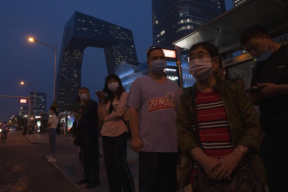 Residents wearing masks wait at a bus stop in Beijing Saturday, Sept. 18, 2021. China's "zero tolerance" strategy of trying to isolate every case and stop transmission of the coronavirus has kept kept the country where the virus first was detected in late 2019 largely free of the disease. (AP Photo/Ng Han Guan)