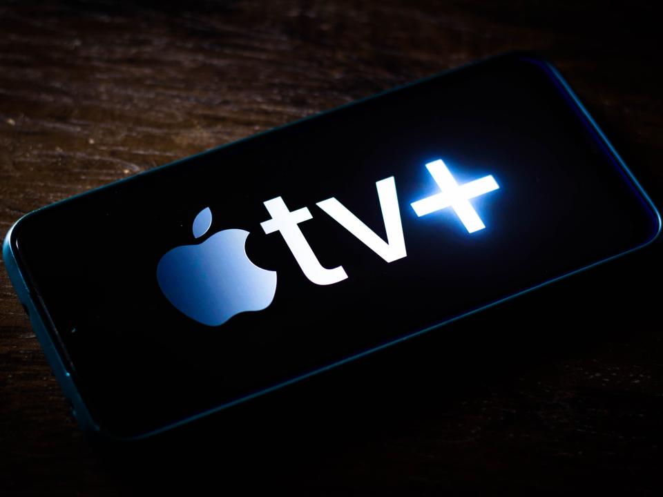 apple tv plus logo on a smartphone on a dark wooden surface