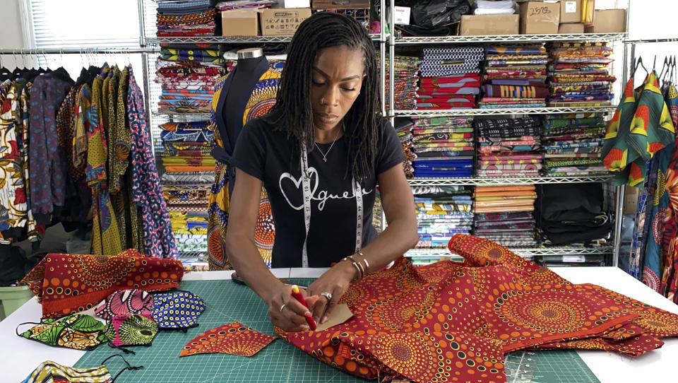 Iguehi James, an Oakland, Calif., fashion entrepreneur, cuts fabric to make a face mask she sells through her apparel company Love Iguehi, Tuesday, Sept. 15, 2020. She received a $5,000 grant from the Oakland African American Chamber of Commerce's "Resiliency Fund," which seeks to help Black-owned businesses stay afloat during the coronavirus pandemic. (AP Photo/Terry Chea)