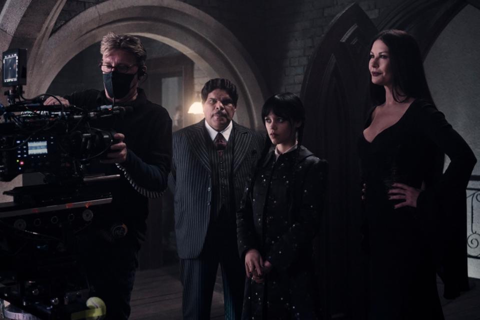 Wednesday. (L to R) Production Coordinator Adrian Sabau, Luis Guzmán as Gomez Addams, Jenna Ortega as Wednesday Addams, Catherine Zeta-Jones as Morticia Adams in Wednesday. Cr. Tomasz Lazar/Netflix © 2022