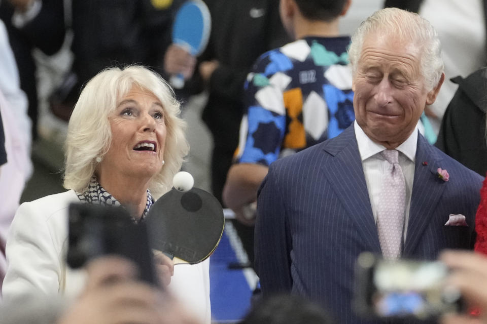 Britain's Queen Camilla plays table tennis as King Charles III looks on during a visit to a gymnasium Thursday, Sept. 21, 2023 in Saint-Denis, outside Paris. (AP Photo/Thibault Camus)