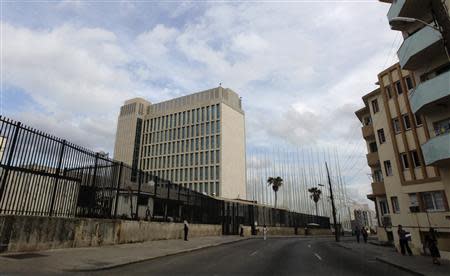 People walk beside the building of the the U.S. diplomatic mission in Cuba, The U.S. Interests Section (USINT), in Havana November 26, 2013. REUTERS/Desmond Boylan