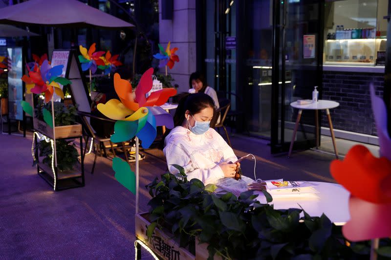 Woman wearing a face mask sits outside a restaurant at a shopping complex in Beijing