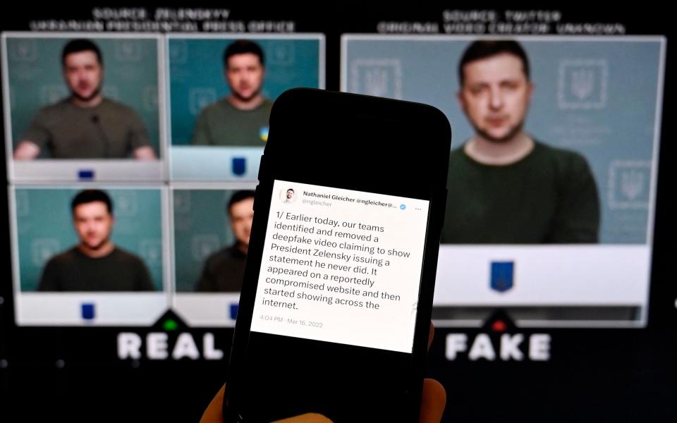 This illustration photo taken on January 30, 2023 shows a phone screen displaying a statement from the head of security policy at META with a fake video (R) of Ukrainian President Volodymyr Zelensky calling on his soldiers to lay down their weapons shown in the background - OLIVIER DOULIERY/AFP via Getty Images