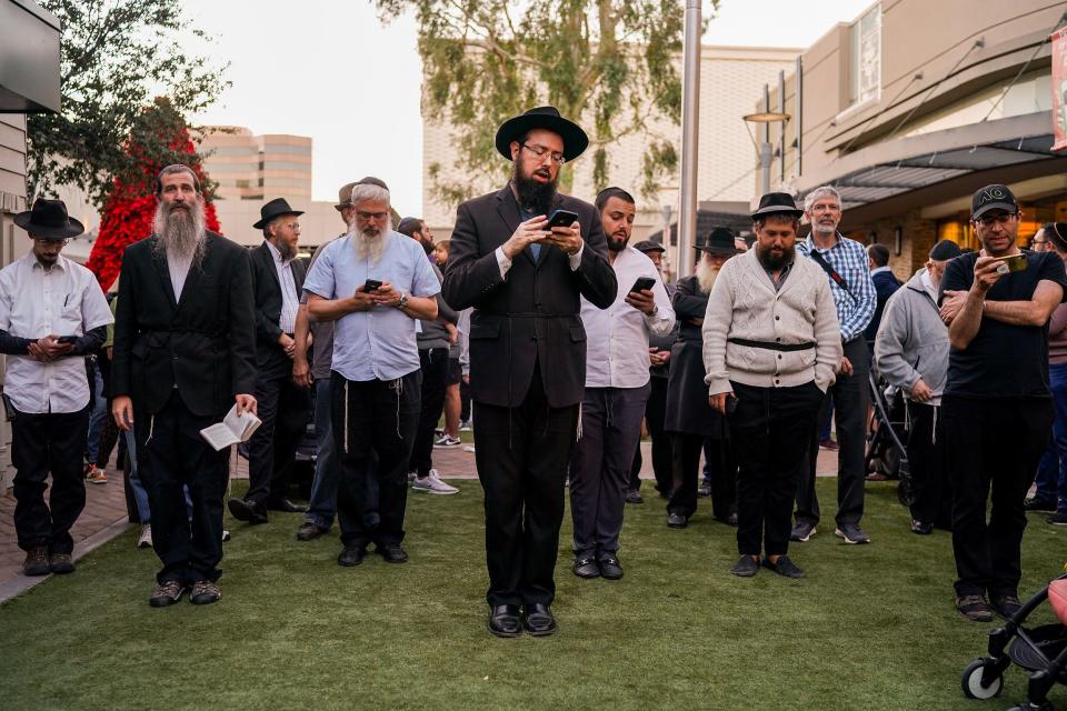 Men pray during Mincha (afternoon prayer service in Judaism) during a celebration for the first night of Hanukkah at the Biltmore Fashion Park on Sunday, Nov. 28, 2021, in Phoenix. The event was hosted by Chabad Lubavitch of Arizona.