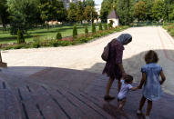 A mother walks with her children outside St. Michael's Ukrainian Orthodox Church of the Moscow Patriarchate during a service on Savior of the Honey Feast Day in Pokrovsk, Donetsk region, eastern Ukraine, Sunday, Aug. 14, 2022. (AP Photo/David Goldman)