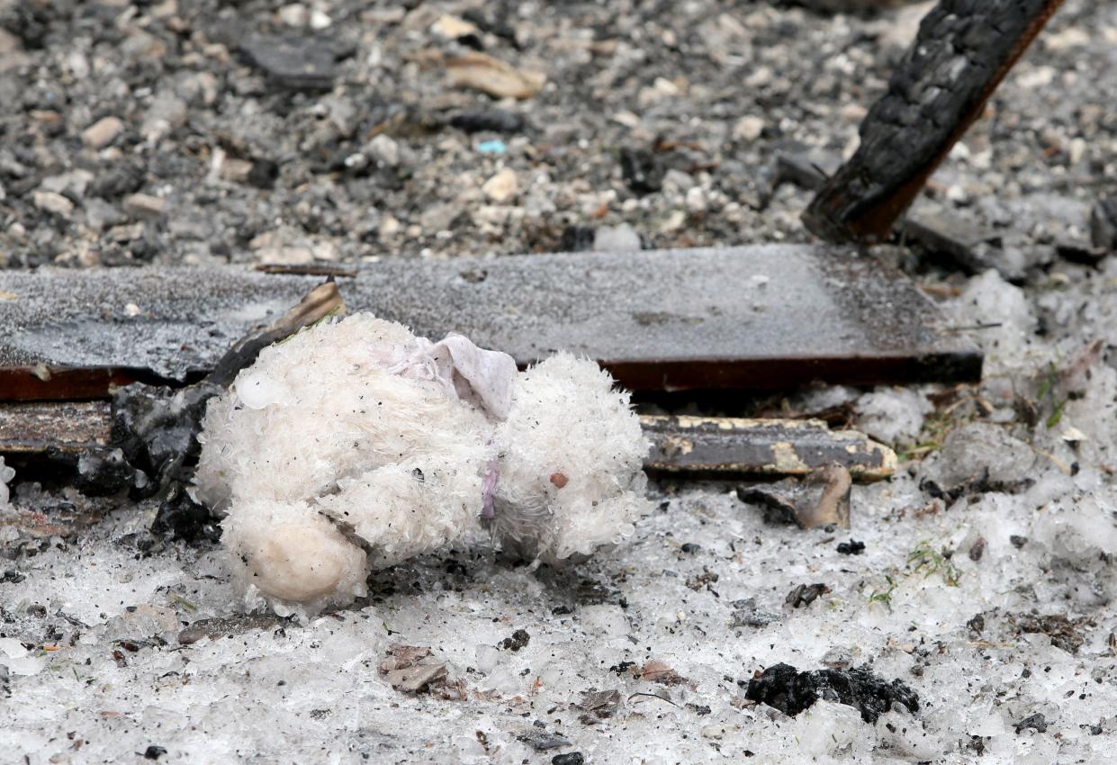 A frozen stuffed animal lies on the ground among some charred wood Monday, Jan. 22, 2024, at the site of a residential fire Sunday night at 222 N. LaPorte Ave. in South Bend. Five children died in the blaze.