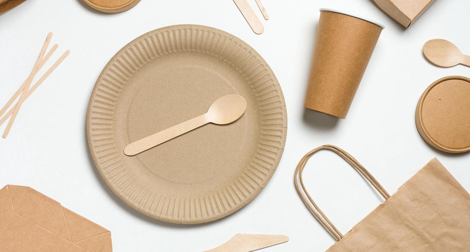 Disposable tableware made of bamboo wood and paper on a white background. The photo is covered in graininess and noise.