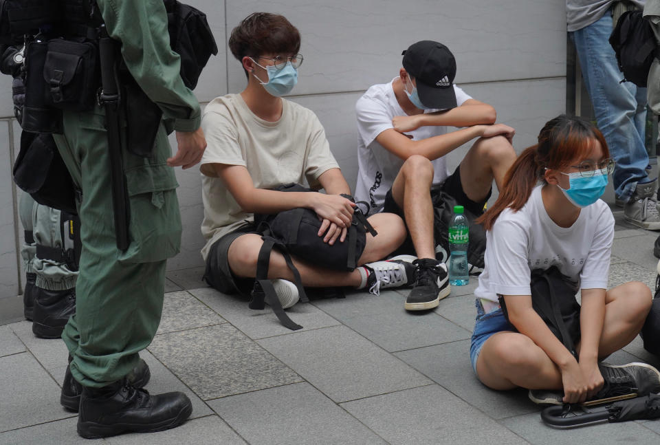 Riot police guard detained anti-government protesters in the Causeway Bay district of Hong Kong, Wednesday, May 27, 2020. Hong Kong police massed outside the legislature complex Wednesday, ahead of debate on a bill that would criminalize abuse of the Chinese national anthem in the semi-autonomous city. (AP Photo/Vincent Yu)