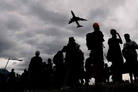 A plane flies over anti-extradition bill protesters as they demonstrate outside the airport in Hong Kong