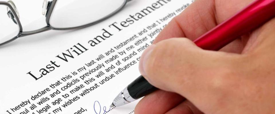 Close up of hand signing a Last Will and Testament document