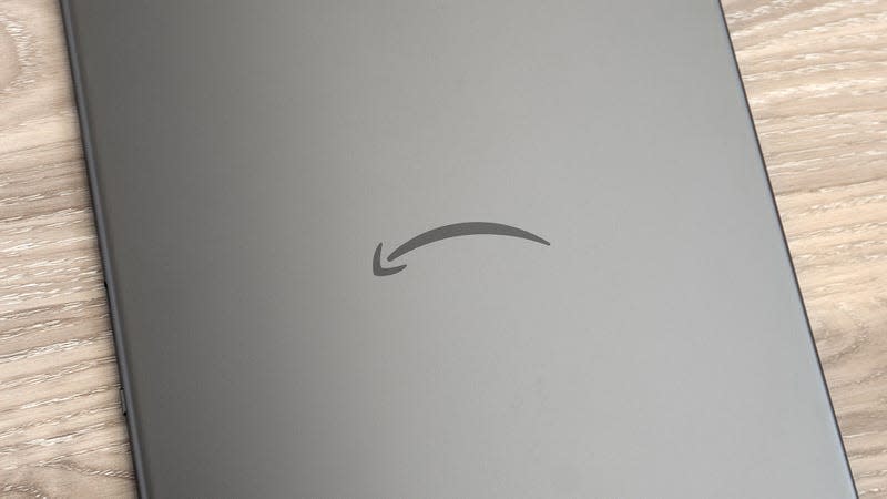 The metal back panel of the Kindle scribe, with the Amazon smile logo in the middle, sitting on a wooden table.