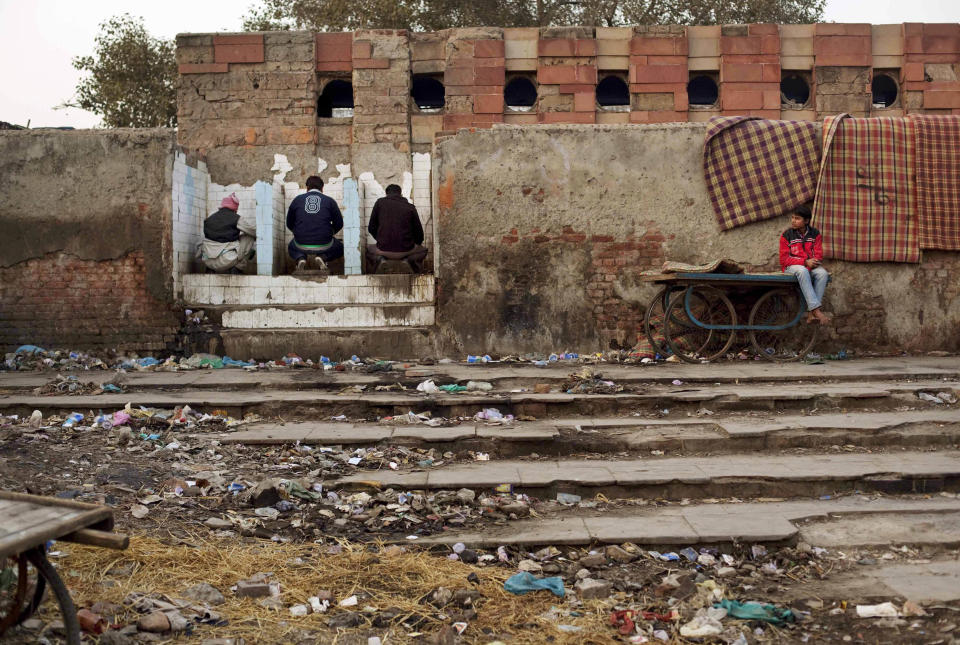 In this photo taken on Feb. 22, 2012, Indian squatters use a public toilet after waking up at Park No. 2 near Jama Masjid in New Delhi, India. For thousands of people struggling at the bottom of India's working class, the Meena Bazaar parking lot and the handful of places like it scattered across New Delhi are cheap refuges in a city where many migrants can't even afford to rent slum shanties. (AP Photo/Kevin Frayer)