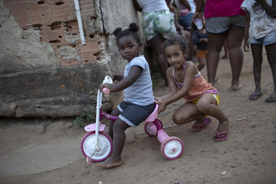 Children play as the adults collect donated food, cleaning supplies, and protective face masks amid the new coronavirus pandemic at the Maria Joaquina Quilombo in Cabo Frio on the outskirts of Rio de Janeiro, Brazil, Sunday, July 12, 2020. The number of people who live in "quilombos," comprised of people descended from runaway slaves, remains uncertain. Authorities planned to count them for the first time in the 2020 census, but the pandemic forced its delay until next year. (AP Photo/Silvia Izquierdo)