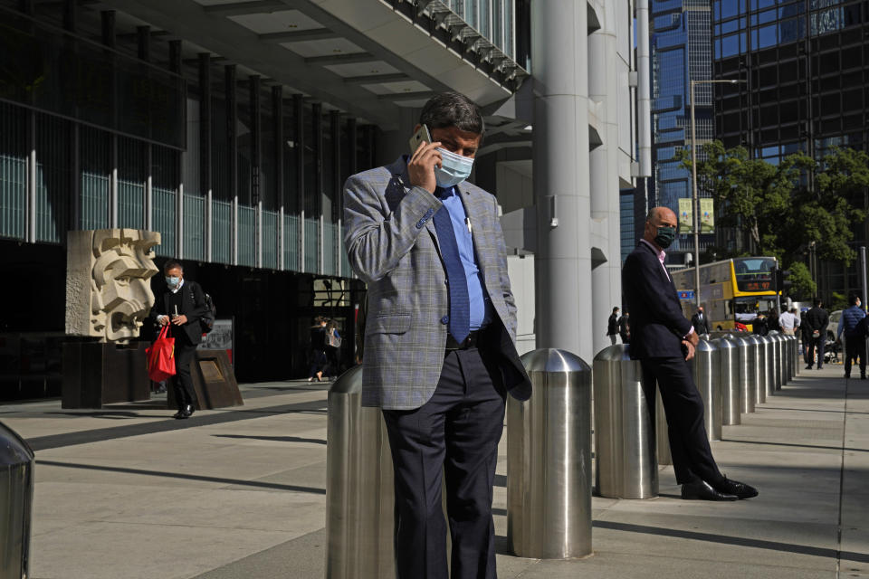 A man wearing a face mask, uses mobile phone outside the HSBC headquarters in Hong Kong on Dec. 1, 2021. The bustling, cosmopolitan business hub of Hong Kong may be losing its shine among foreign companies and expatriates with its stringent anti-pandemic rules requiring up to 21 days of quarantine for new arrivals. (AP Photo/Kin Cheung)