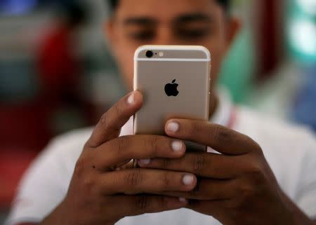 FILE PHOTO - A salesman checks a customer's iPhone at a mobile phone store in New Delhi, India, July 27, 2016. REUTERS/Adnan Abidi/File photo