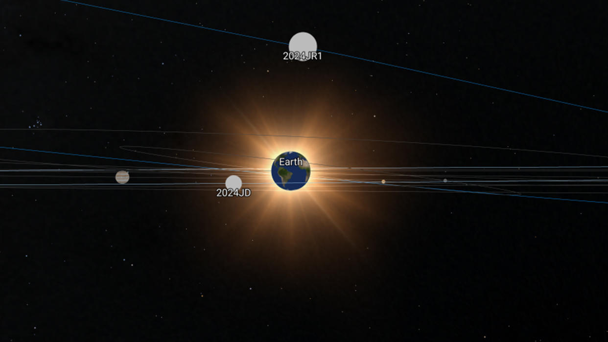  An illustration of the solar system showing two rocks flying close by earth. 
