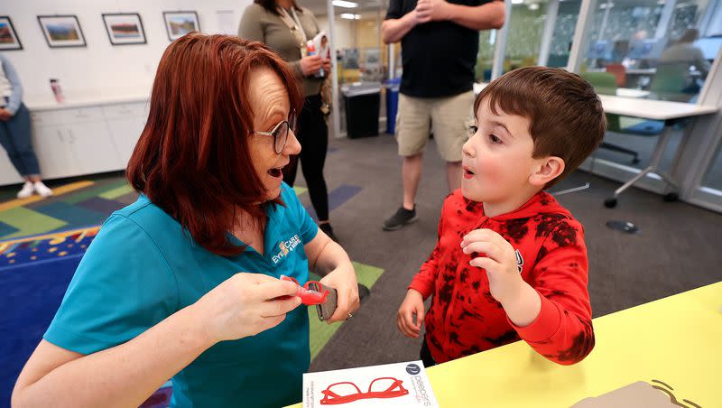 Melanie Robbins, EyeCare4Kids community outreach coordinator, gives Brody Wright, 4, a free pair of blue light glasses after a vision screening with EyeCare4Kids at the Salt Lake Public Library Sprague branch in Salt Lake City on Wednesday, April 26, 2023.