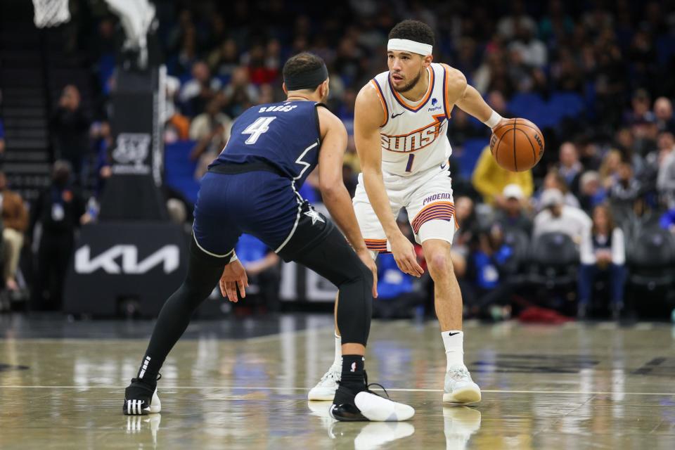 Phoenix Suns guard Devin Booker (1) controls the ball from Orlando Magic guard Jalen Suggs (4) in the first quarter at the Kia Center in Orlando on Jan. 28, 2024.