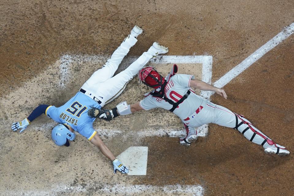 Milwaukee Brewers' Tyrone Taylor scores past Philadelphia Phillies catcher J.T. Realmuto during the eighth inning of a baseball game Friday, Sept. 1, 2023, in Milwaukee. Taylor scored on an error after a ball hit by Owen Miller. (AP Photo/Morry Gash)