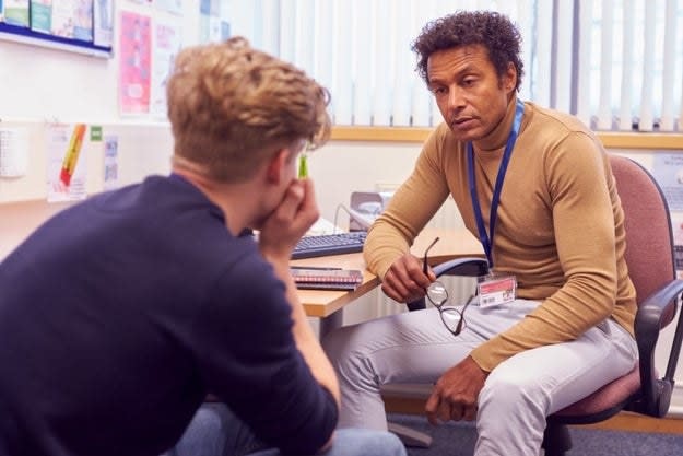 A teacher speaks with a student in his office