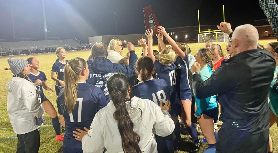 The Parrish Community High girls soccer team raises the championship trophy after defeating Braden River High, 2-1, for the Class 5A-District 10 title. It was the Bulls third straight district crown.