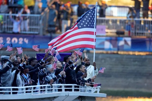 <p>Richard Pelham/Getty</p> Team USA waves the flag during the opening ceremony