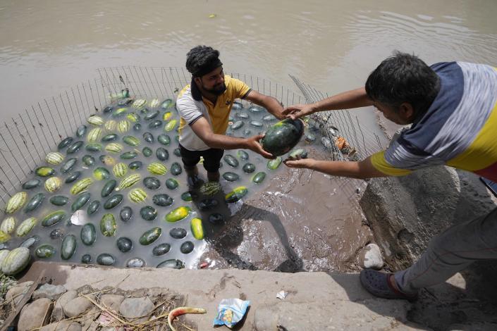 A man sells watermelons from a canal on a hot summer afternoon in Jammu, India, on Thursday.  (Channi Anand / AP)