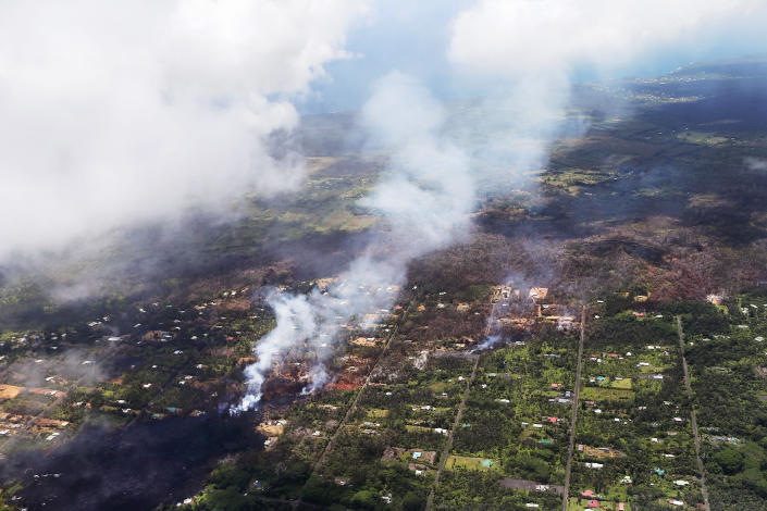 <p>Smoke and volcanic gases rise as lava (L) cools in the Leilani Estates neighborhood, in the aftermath of eruptions and lava flows from the Kilauea volcano on Hawaii’s Big Island, on May 11, 2018 in Pahoa, Hawaii. (Photo: Mario Tama/Getty Images) </p>