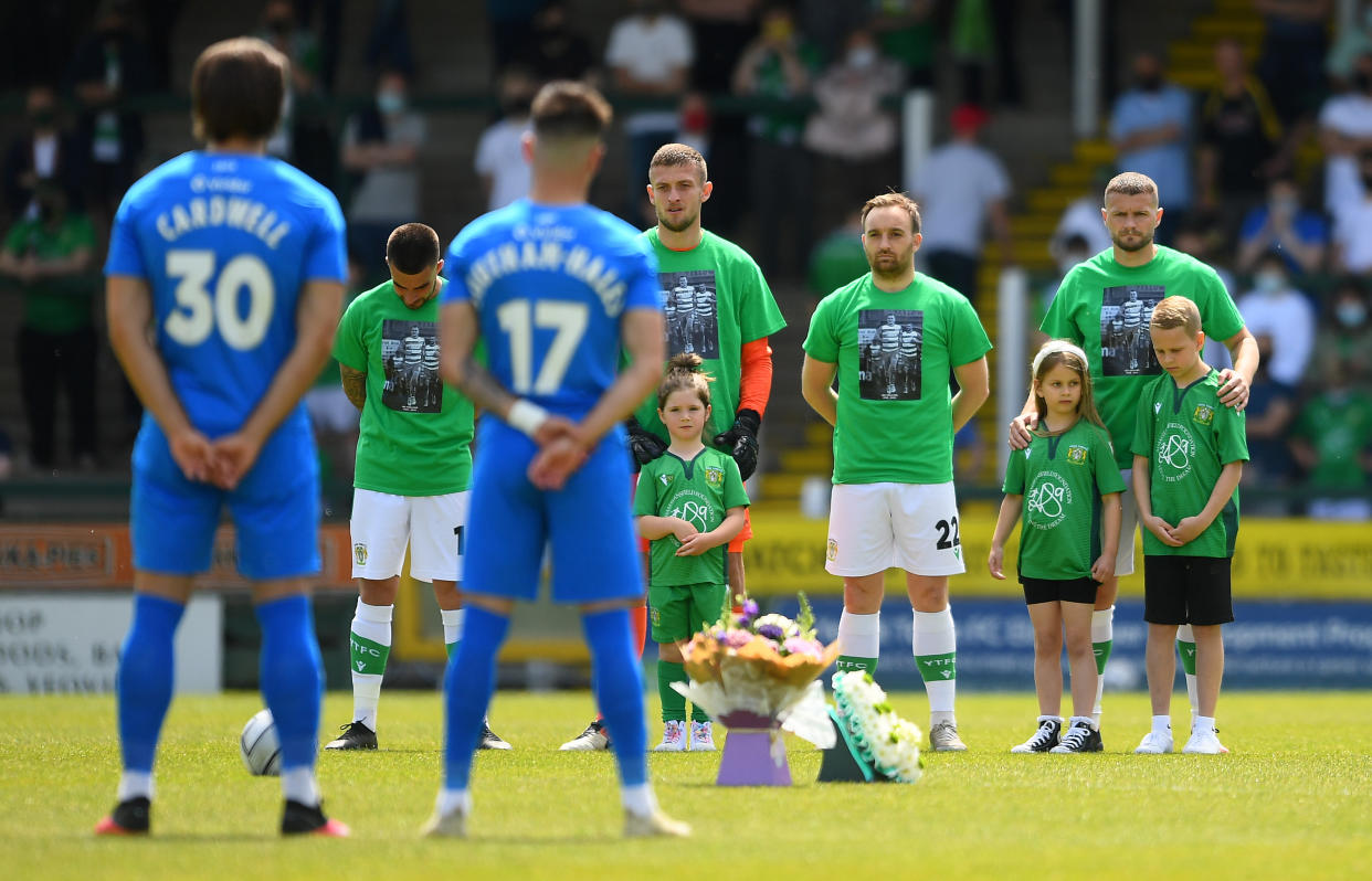 Players of Yeovil and Stockport, alongside the family of Lee Collins, hold a minutes applause as a mark of respect to Lee Collins.