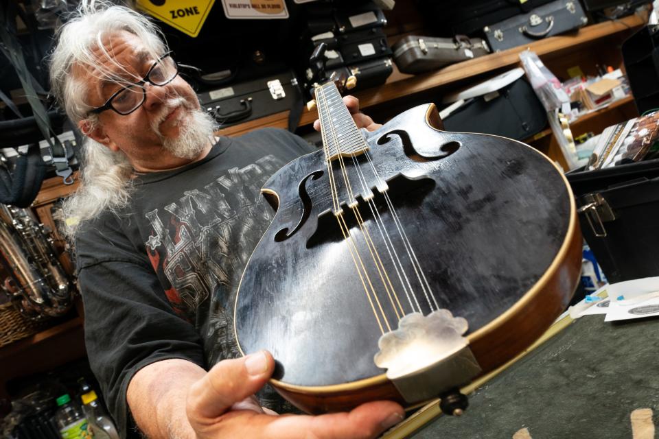 After putting on new strings and setting the bridge, S. Vincent Ward, a local musician and instrument repairman, admires the Shutt mandolin he is helping repair at Hayes House of Music. "This is the nicest mandolin I've ever played on," he said after a few strums.