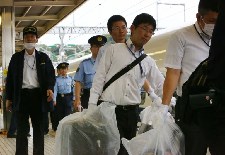 Police carry evidence from a Nozomi 255 shinkansen bullet train at Odawara station on June 30, 2015 after a man set himself ablaze on board