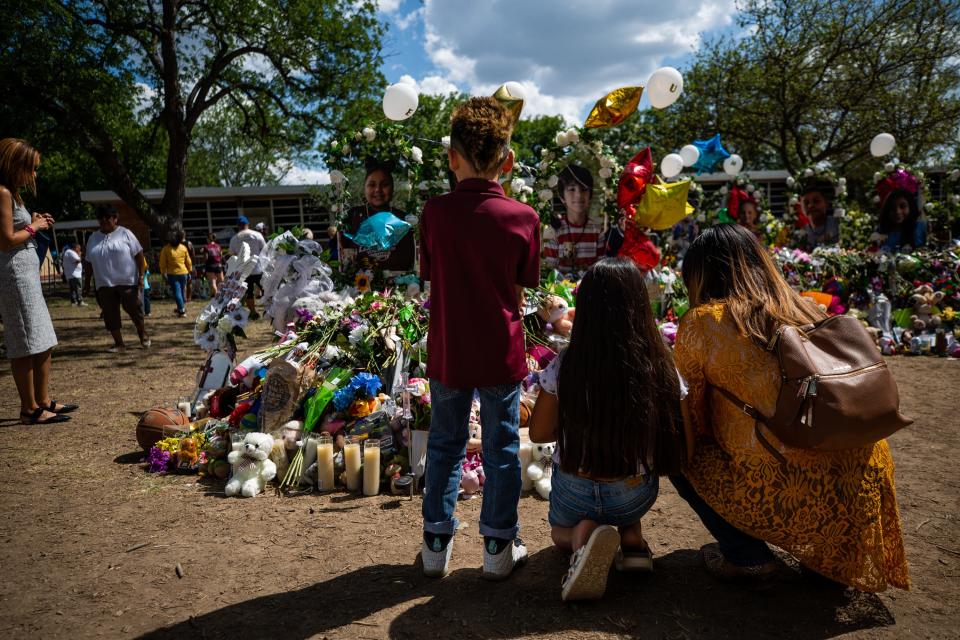 Zayin Zuniga, 10, gazes at piles of flowers and balloons left in front of crosses at Robb Elementary in Uvalde on June 1, 2022, memorializing the 19 children and two teachers fatally shot after a gunman entered the building the week before.