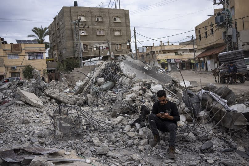 Ibrahim Hasouna, center, the sole survivor among his family, sits amidst the debris of his bombed home in Rafah.