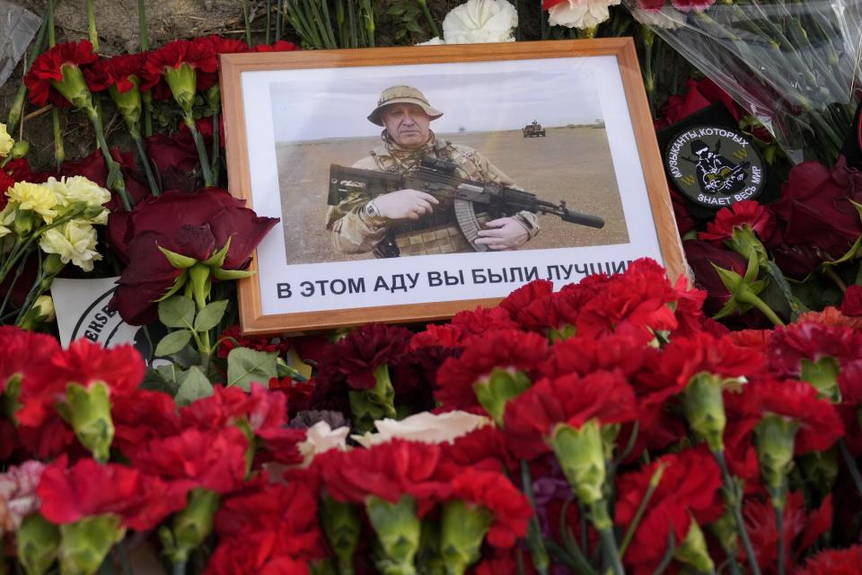 FILE - Flowers along with an image of the owner of private military company Wagner Group, Yevgeny Prigozhin, with the message written in Russian: 'In this hell you were the best' placed at an informal memorial next to the former "PMC Wagner Center," in St. Petersburg, Russia, Friday, Aug. 25, 2023. The final two months of Yevgeny Prigozhin's life are shrouded in mystery. When the Russian mercenary leader staged a mutiny against the country's military in June, President Vladimir Putin decried it as "treason" and vowed punishment, but then allowed the Wagner boss to walk free. Two months later, Prigozhin's business jet plummeted from the sky. (AP Photo/Dmitri Lovetsky, File)