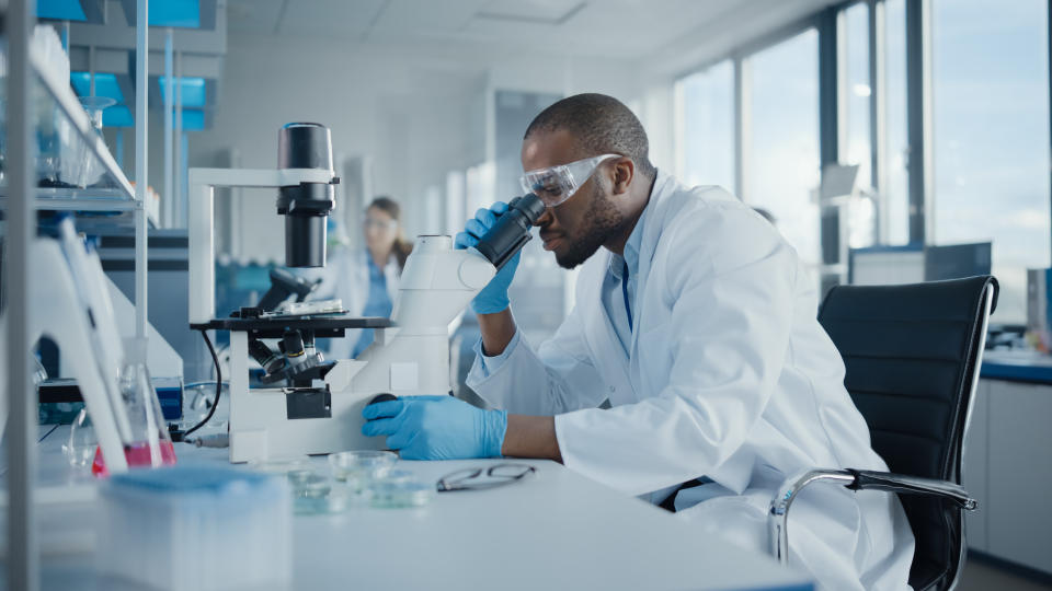 a man in a lab looking through a microscope