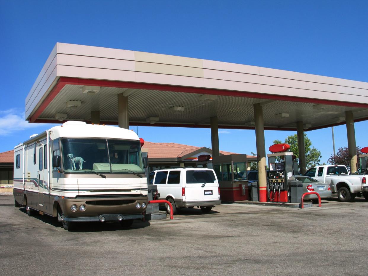 A motorhome and several other vehicles at a gas station.