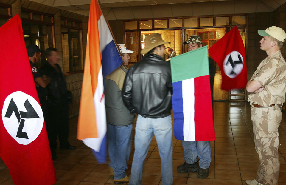 FILE - In this June 11 2004, file photo, supporters of the Afrikaner Resistance Movement (AWB) display an old South African flag, second from left, an old Afrikaner "Vierkleur" flag and swastika-like flags as they await the release of their leader, Eugene Terre'Blanche from prison in Potchefstroom, South Africa where he was granted parole after serving three years of an effective five year sentence for the 1996 attempted murder of a black security guard. South Africa's Equality Court has restricted the display of the old apartheid-era flag in a ruling issued Wednesday Aug. 21, 2019, that it's gratuitous use amounts to hate speech and racial discrimination. (AP Photo, FILE)