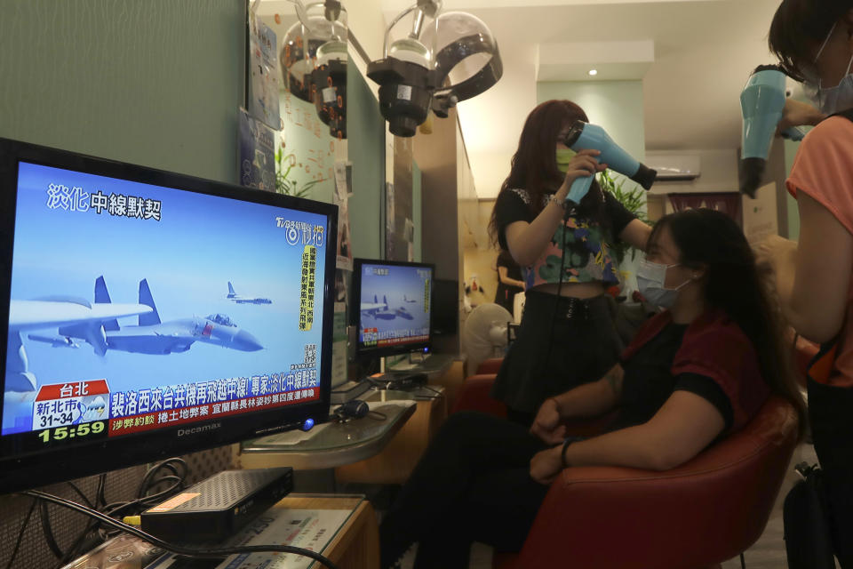 A customer watches a news report on the recent tensions between China and Taiwan, at a beauty salon in Taipei, Taiwan, Thursday, Aug. 4, 2022. Taiwan canceled airline flights Thursday as the Chinese navy fired artillery near the island in retaliation for a top American lawmaker’s visit. (AP Photo/Chiang Ying-ying)