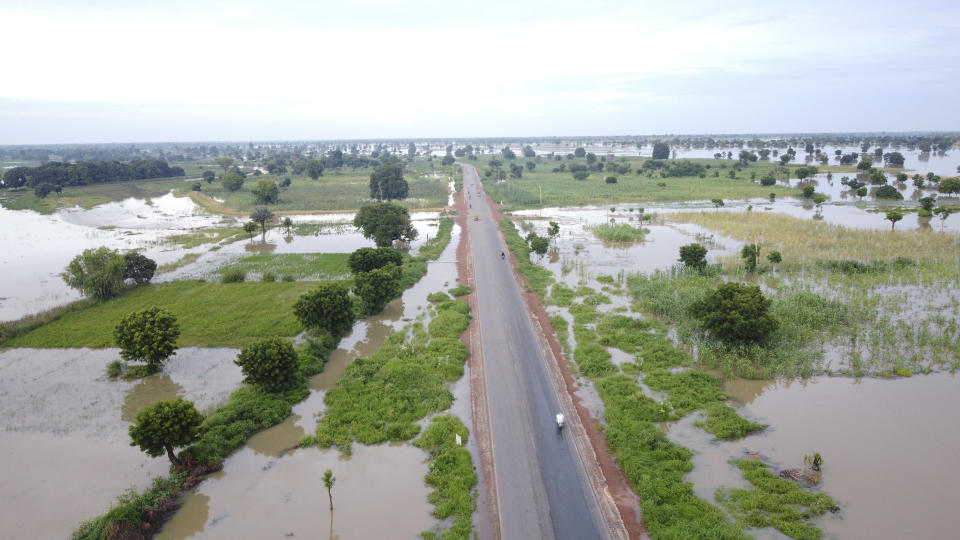 FILE - People travel on the road with flooded farmlands after heavy rainfall in Hadeja, Nigeria, Sept 19, 2022. Authorities in Nigeria say they have activated a national response plan for another round of deadly floods blamed mainly on climate change and infrastructure problems. The West African nation's National Emergency Management Agency said Thursday, July 6, 2023 it has begun to work based on dire forecasts by seeking air support for search and rescue missions while stockpiling relief materials. (AP Photo, file)