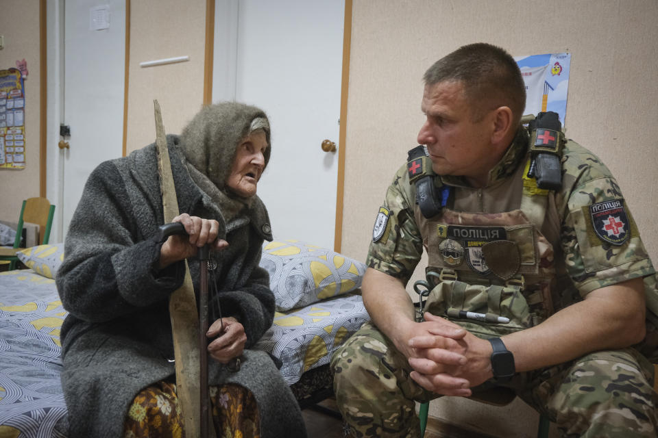In this photo provided by the Ukrainian National Police of Donetsk region, 98-year-old Lidia Lomikovska chats with a police officer in a shelter after she escaped Russian-occupied territory in the Donetsk region, Ukraine, April 26, 2024. Lomikovska left the frontline town of Ocheretyne last week by walking almost 10 km (6 miles) alone, after Russian troops entered it and fighting intensified. (Ukrainian National Police of Donetsk region via AP)