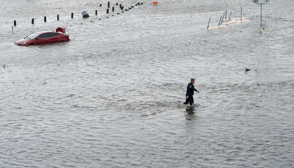 A police officer wades through floodwaters in Alvin, Texas, about 25 miles southeast of Houston. (Photo: Rick Wilking / Reuters)