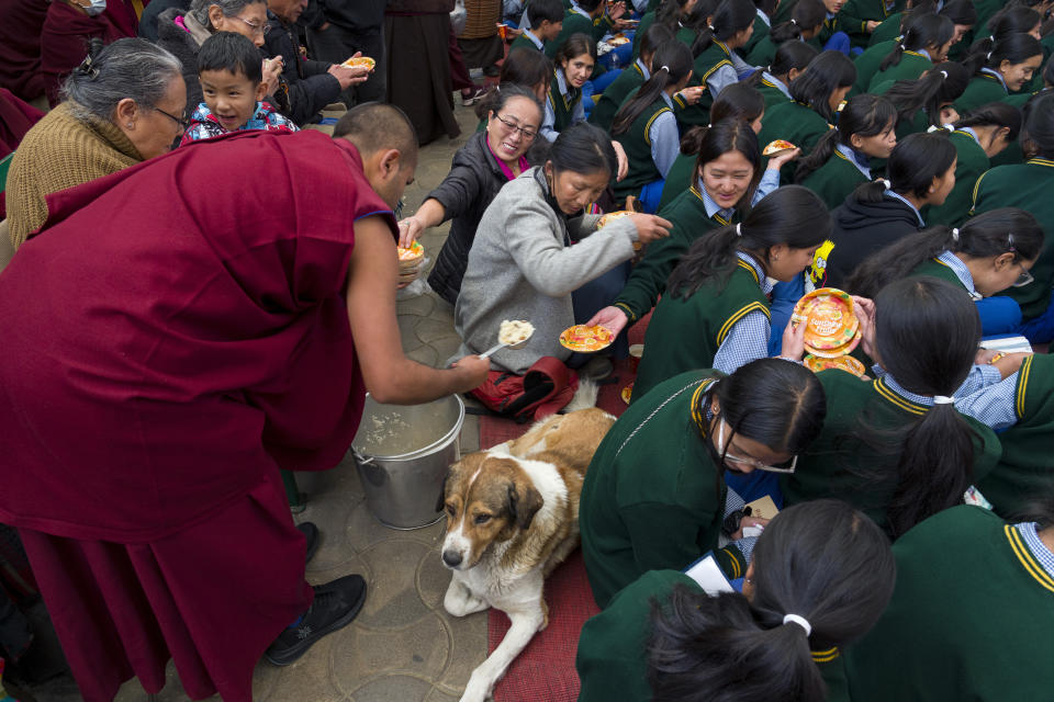 An exile Tibetan Buddhist monk distributes sweetened rice as refreshments at an event marking the anniversary of the awarding of the Nobel Peace Prize to the Dalai Lama in Dharamshala, India, Sunday, Dec. 10, 2023. (AP Photo/Ashwini Bhatia)