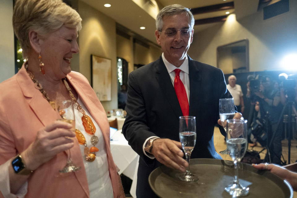 Incumbent Georgia Secretary of State Brad Raffensperger, grabs a glass of champagne to toast with his wife Tricia after declaring victory just before midnight at an election night party Tuesday evening, May 24, 2022 at a small restaurant in Peachtree Corners, Ga. (AP Photo/Ben Gray)