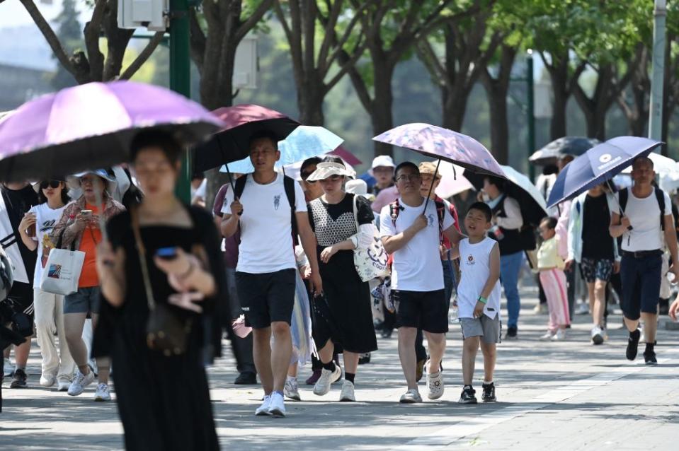 People shelter from the sun under umbrellas after visiting the Forbidden City during a heatwave in Beijing on June 24, 2023. Beijing recorded its third consecutive day of 40 degree Celsius weather, the first time since records began. (Photo by GREG BAKER / AFP) (Photo by GREG BAKER/AFP via Getty Images)<span class="copyright">AFP via Getty Images</span>