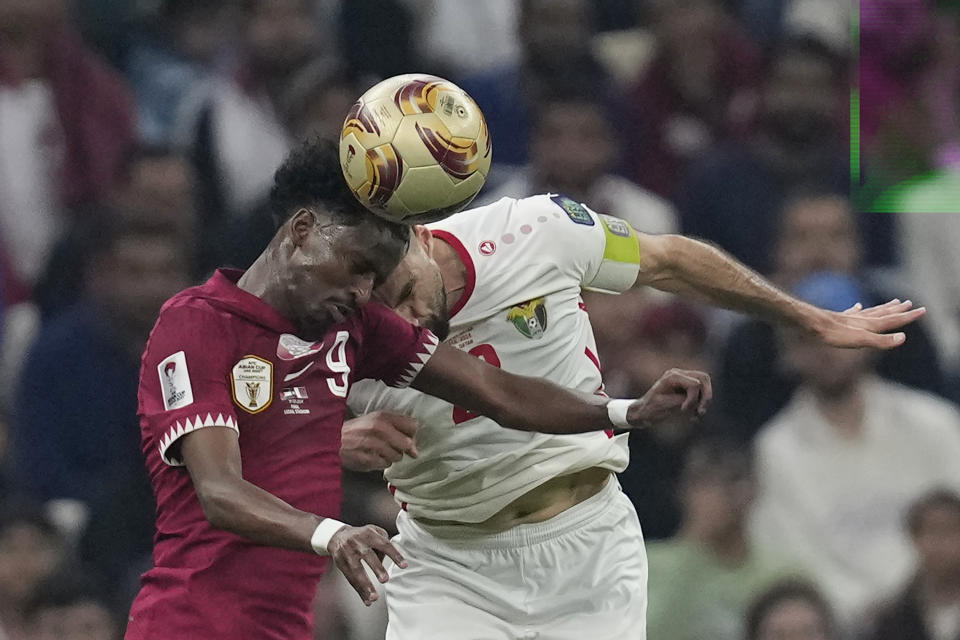 Qatar's Yusuf Abdurisag, left, and Jordan's Ehsan Haddad vie for the ball during the Asian Cup final soccer match between Qatar and Jordan at the Lusail Stadium in Lusail, Qatar, Saturday, Feb. 10, 2024. (AP Photo/Thanassis Stavrakis)