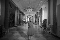 <p>Patricia Nixon shows off the White House's Cross Hall decorated for Christmas with holly and trees. </p>